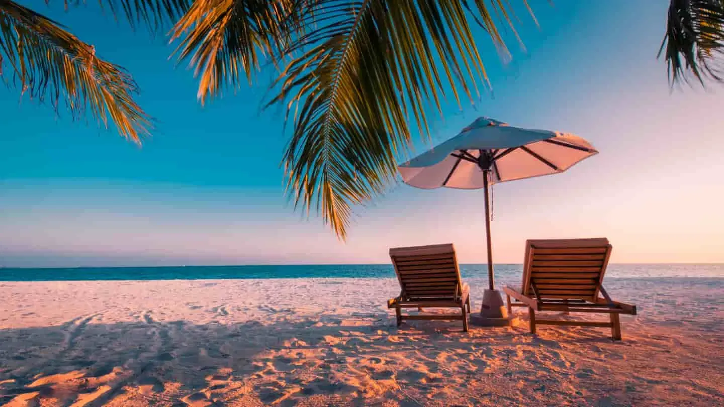 Two chairs facing a tropical beach at sunset